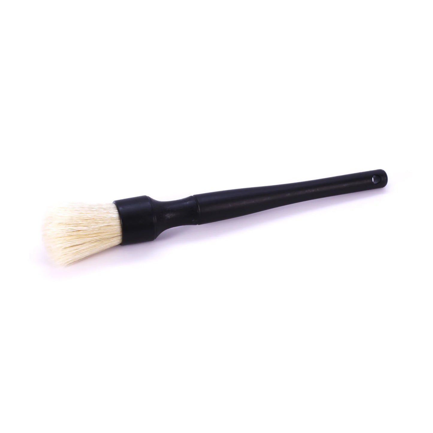 Studio photograph of a black-handled detailing brush featuring soft cream bristles, a silver ferrule, and a small hanging hole at the tapered end
